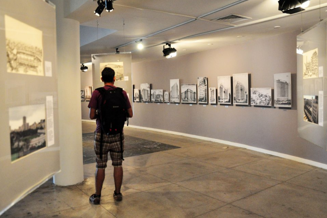 Parte interna do Parque das Ruínas, com exposição fotográfica em cartaz. Há um homem na imagem observando a exposição.