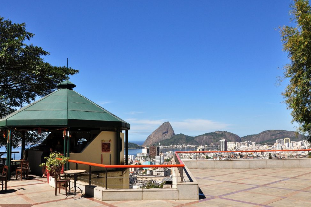 Mirante, com vista para a Baía de Guanabara, céu azul ensolarado e a lanchonete do ponto turístico.