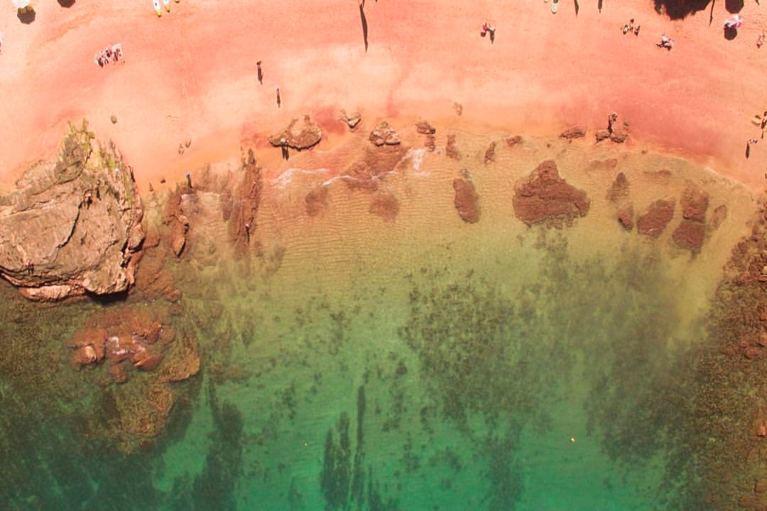 Imagem aérea da Praia do Forno, que fica próxima ao Mirante do Forno, possuindo uma areia vermelha e um mar calmo e transparente.