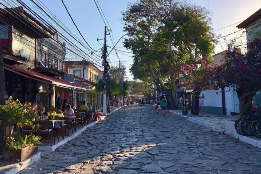 Rua das Pedras ensolarada, com pessoas caminhando na calçada e outras andando na própria rua.