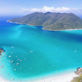 Vista aérea de Arraial do Cabo, o caribe brasileiro, em que possível ver uma parte da faixa de areia, algumas ilhas e o mar azul.