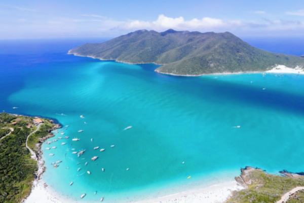 Vista aérea de Arraial do Cabo, o caribe brasileiro, em que possível ver uma parte da faixa de areia, algumas ilhas e o mar azul.